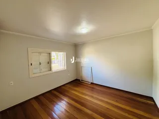Sala de estar com piso de madeira e janela em um imóvel no Brasil.