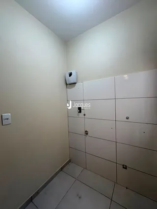 Foto de um corredor interno de um imóvel com paredes claras e piso de cerâmica.