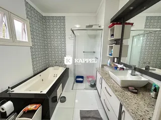 Banheiro com banheira e box de vidro e revestimento cerâmico.