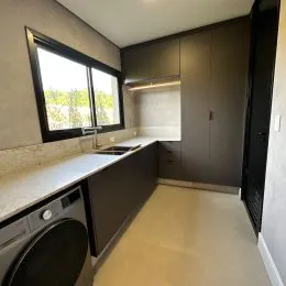 Foto interna de uma cozinha com armários superiores e bancada clara.