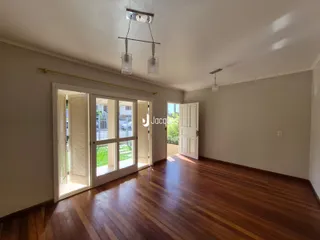Sala de estar com piso de madeira e portas de vidro que dão acesso ao exterior.
