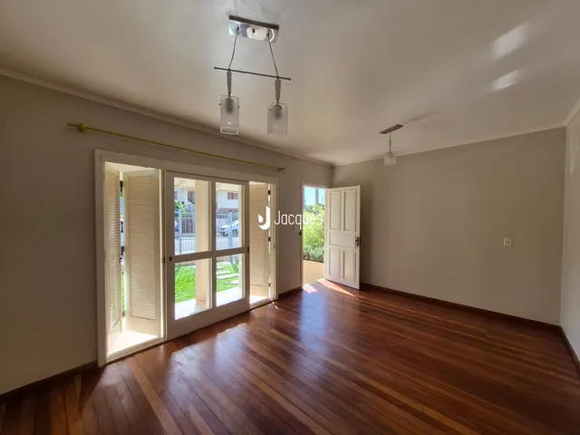 Sala de estar com piso de madeira e portas de vidro que dão acesso ao exterior.