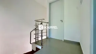 Hall de entrada com escada de metal e paredes brancas.