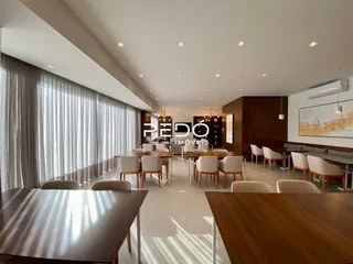 Um corredor interno com cortinas claras e piso de madeira.