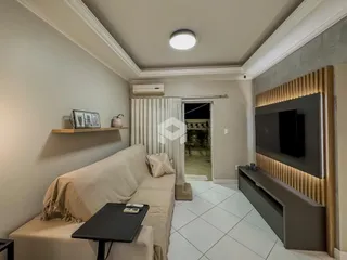 Sala de estar com sofá e painel de televisão em um apartamento.