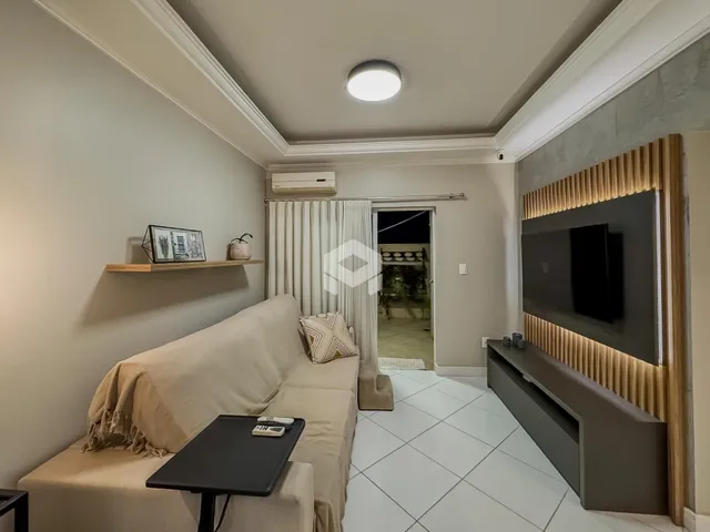 Sala de estar com sofá e painel de televisão em um apartamento.