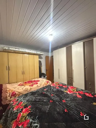 Quarto com cama decorada e painéis de madeira na parede.