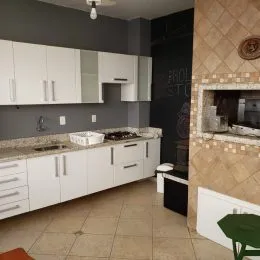 Cozinha com armários brancos e bancadas claras em um imóvel.