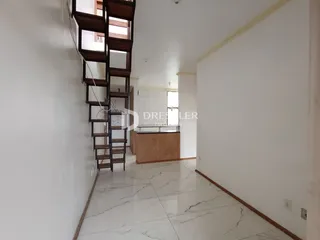 Corredor interno de uma residência com piso de mármore claro e escadaria de madeira escura.