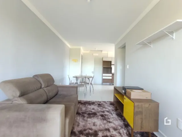 Imagem de uma sala de estar clara com sofá e corredor em um imóvel.