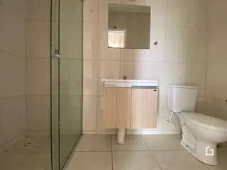 Banheiro com box de vidro e revestimento cerâmico nas paredes.