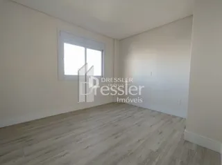 Sala de estar com piso de madeira clara e janela.