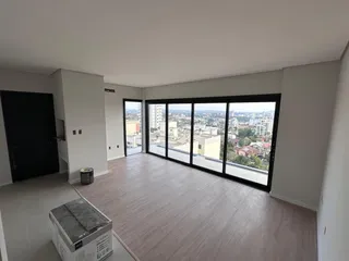 Sala de estar com piso de madeira e grandes janelas com vista para a cidade.