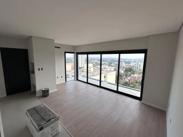 Sala de estar com piso de madeira e grandes janelas com vista para a cidade.
