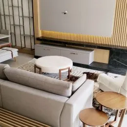 Sala de estar com sofá branco e tapete em ambiente interno.