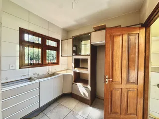 Foto de uma cozinha com bancada e armários brancos e piso de cerâmica.