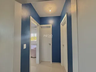 Hall de entrada com paredes azuis e portas brancas em uma residência.