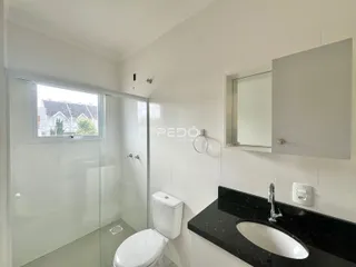 Banheiro moderno com box de vidro e revestimento branco.
