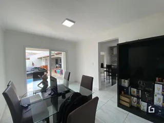 Interior de uma sala com mesa de vidro e portas de vidro que se abre para um corredor.