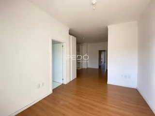 Interior de um ambiente com piso de madeira e paredes brancas.