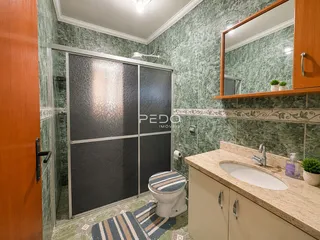 Foto de um banheiro com revestimento de azulejos verdes e bancada de mármore.