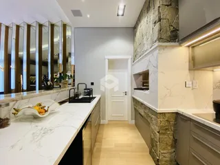 Vista da cozinha moderna com bancadas de mármore e piso de madeira clara.