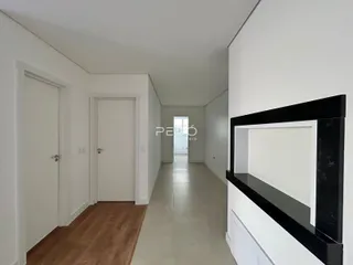 Corredor interno de uma residência com piso de madeira e paredes brancas.