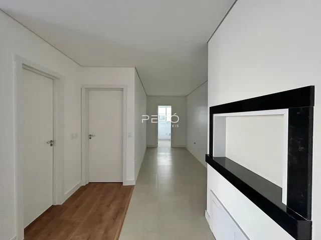Corredor interno de uma residência com piso de madeira e paredes brancas.