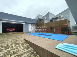 Vista da fachada de uma residência com garagem e área pavimentada.