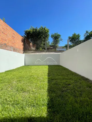 Vista externa de um gramado verde com muros brancos em uma propriedade.