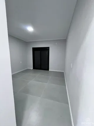 Corredor interno com piso claro e paredes brancas.