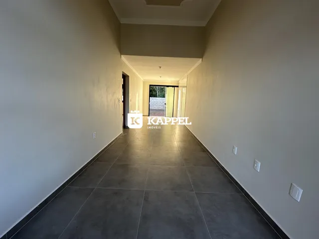 Corredor interno de uma residência com paredes claras e piso escuro.