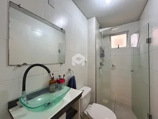 Foto de um banheiro com azulejos brancos e box de vidro.