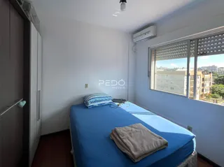 Quarto com cama azul e janela mostrando a vista externa.