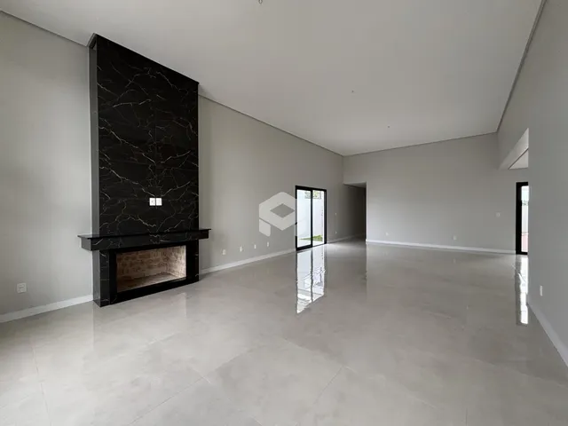 Interior de uma sala ampla com piso claro e parede de destaque escura.