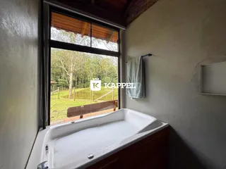 Foto de um banheiro mostrando uma banheira com vista para a vegetação externa.