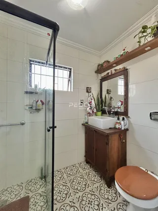 Foto interna de um banheiro com piso de cerâmica e box de vidro.