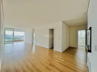 Sala de estar ampla com piso de madeira clara e porta de vidro.