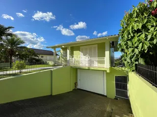 Fachada de uma casa verde em Lajeado, Brasil, com portão branco.