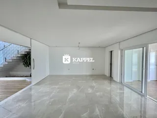 Sala ampla com piso de porcelanato claro e paredes brancas.