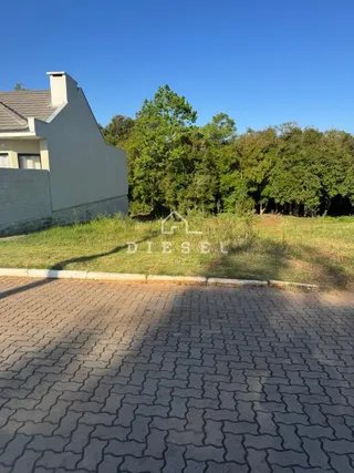 Vista da fachada de uma residência em Lajeado, Brasil, com área de pavimentação e vegetação ao fundo.