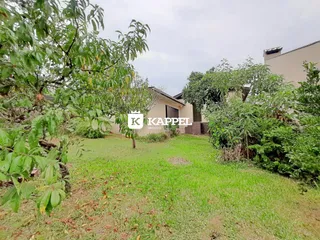 Vista externa do terreno com gramado e vegetação ao redor da residência.
