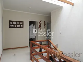Hall com paredes brancas e piso de madeira na área interna da propriedade.