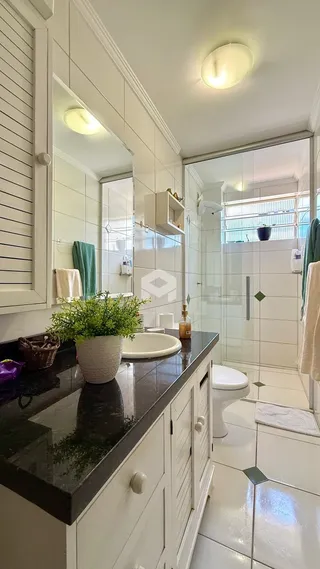 Banheiro moderno com revestimento branco e bancada escura.