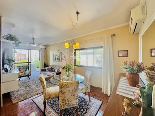Sala de estar com piso de madeira e grandes janelas no interior de uma residência.