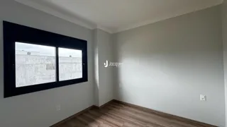 Vista interna de um cômodo com piso de madeira e grande janela.