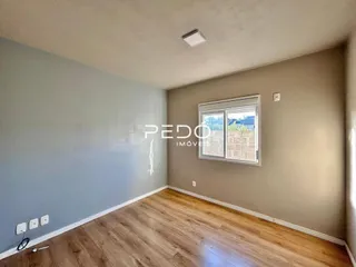 Ambiente interno de uma sala com piso de madeira clara e paredes cinzas.