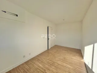 Vista interna de um cômodo com piso de madeira clara e paredes brancas.