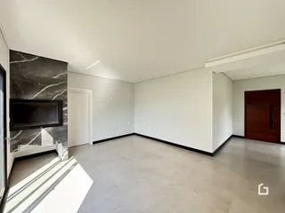 Uma sala de estar ampla com piso de cerâmica cinza e parede de mármore escura.