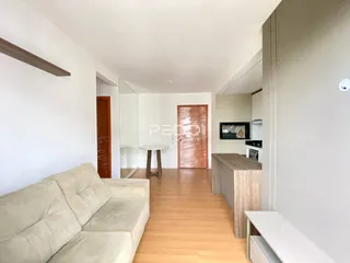 Hall de entrada com piso de madeira clara e sofá no primeiro plano.